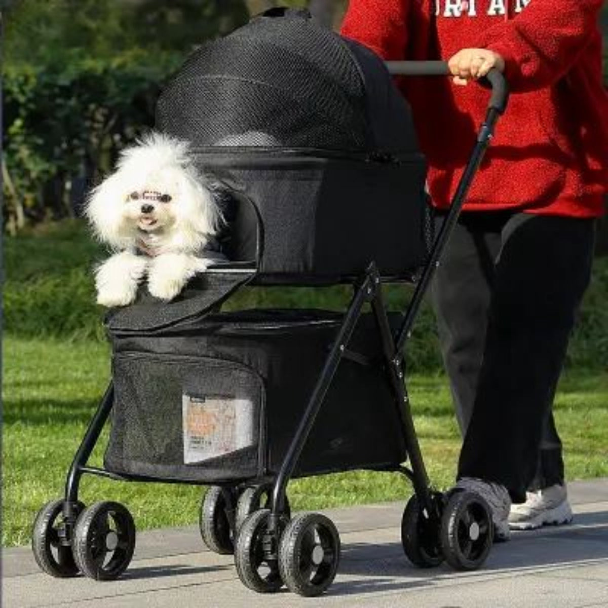 Poussette PetStroller noire avec chien blanc à l’intérieur, tablette latérale et sac