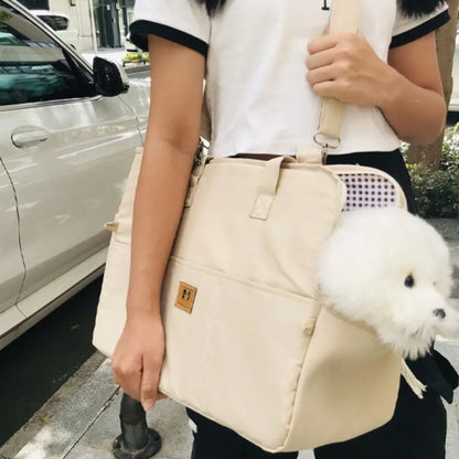 Sac voiture pour chien beige porté en bandoulière, chien blanc sortant la tête.