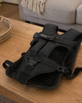 Sac de transport pour chien noir, bretelles et sangles réglables, boucles de fermeture.